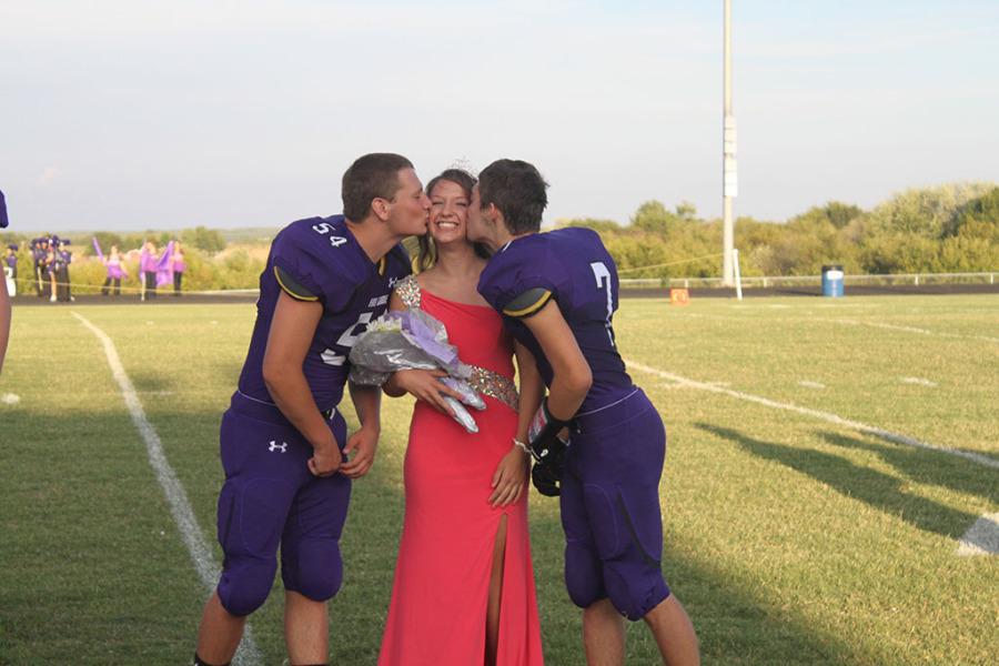 Austin Squires and Dylan Lucas kiss Homecoming Queen Kayli Coddington. 
