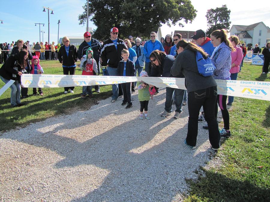 NHS Members help hold the ribbon while a participant cuts the ribbon for the start of the walk. 