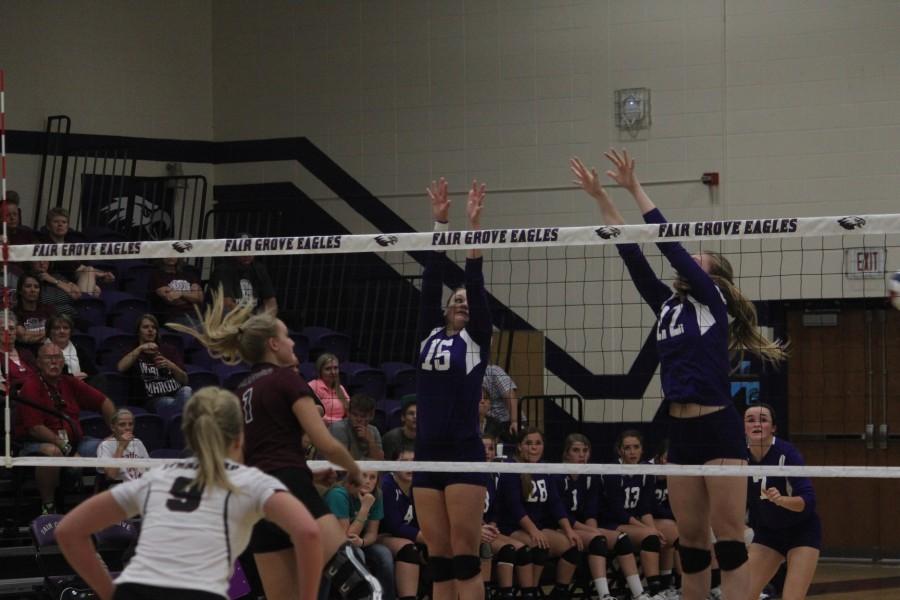 Alana Findley and Makenna Hill 
jump to block the ball to score a point in home district tournament game.  
