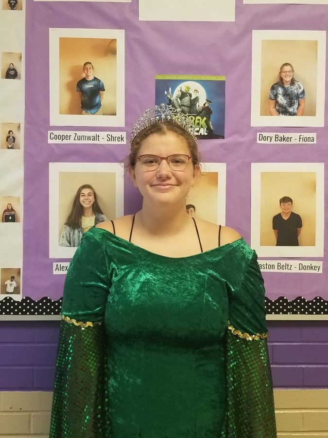 Dory Baker (12) in her Fiona costume standing in front of the Shrek bulletin board.