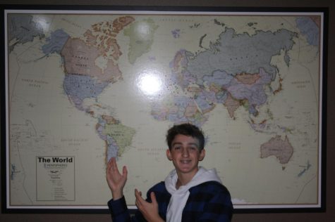 Brandon Kandlbinder in front of a map of the world.