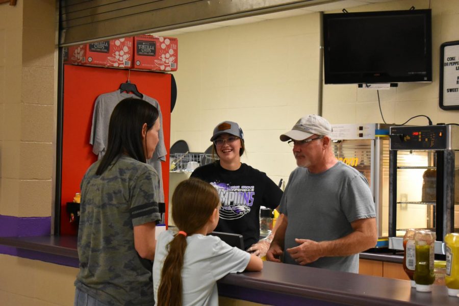 Bryleigh Mays and Ken Muncy working concessions serving Tonya Peck.