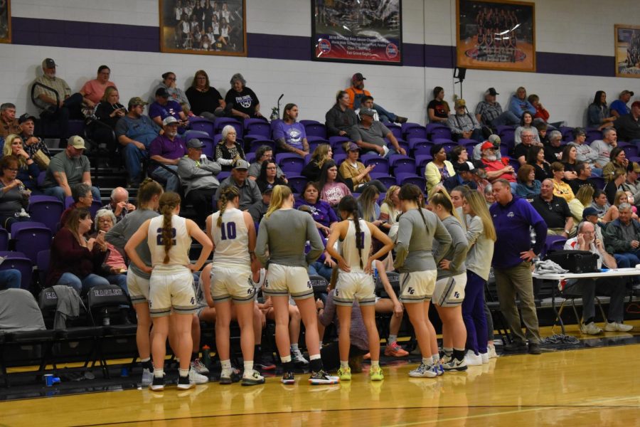 Coach Talbert and the girls basketball team having a discussion during a timeout at a girls basketball game.