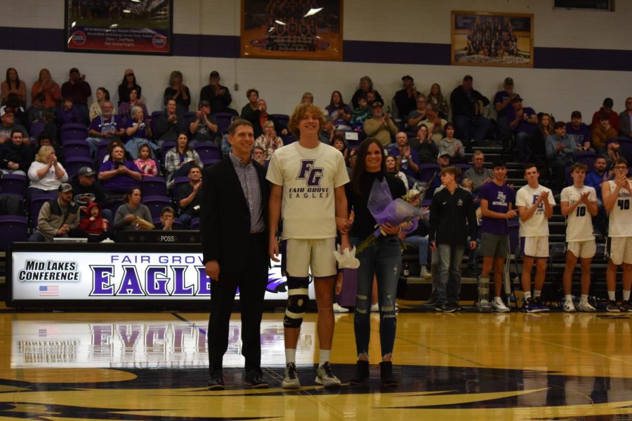 Devin Carroll (center) standing with his father Brendan Carroll (left) and his mother Jennifer Carroll (right), at Boys Basketball Senior Night (2/8). (photo taken by Samantha Saylor)