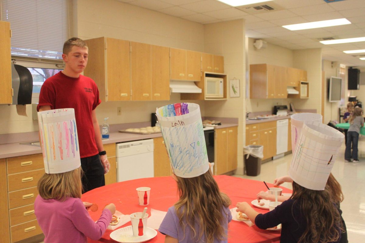 Randy Hodges (10) helping students prepare their pizzas to be made.