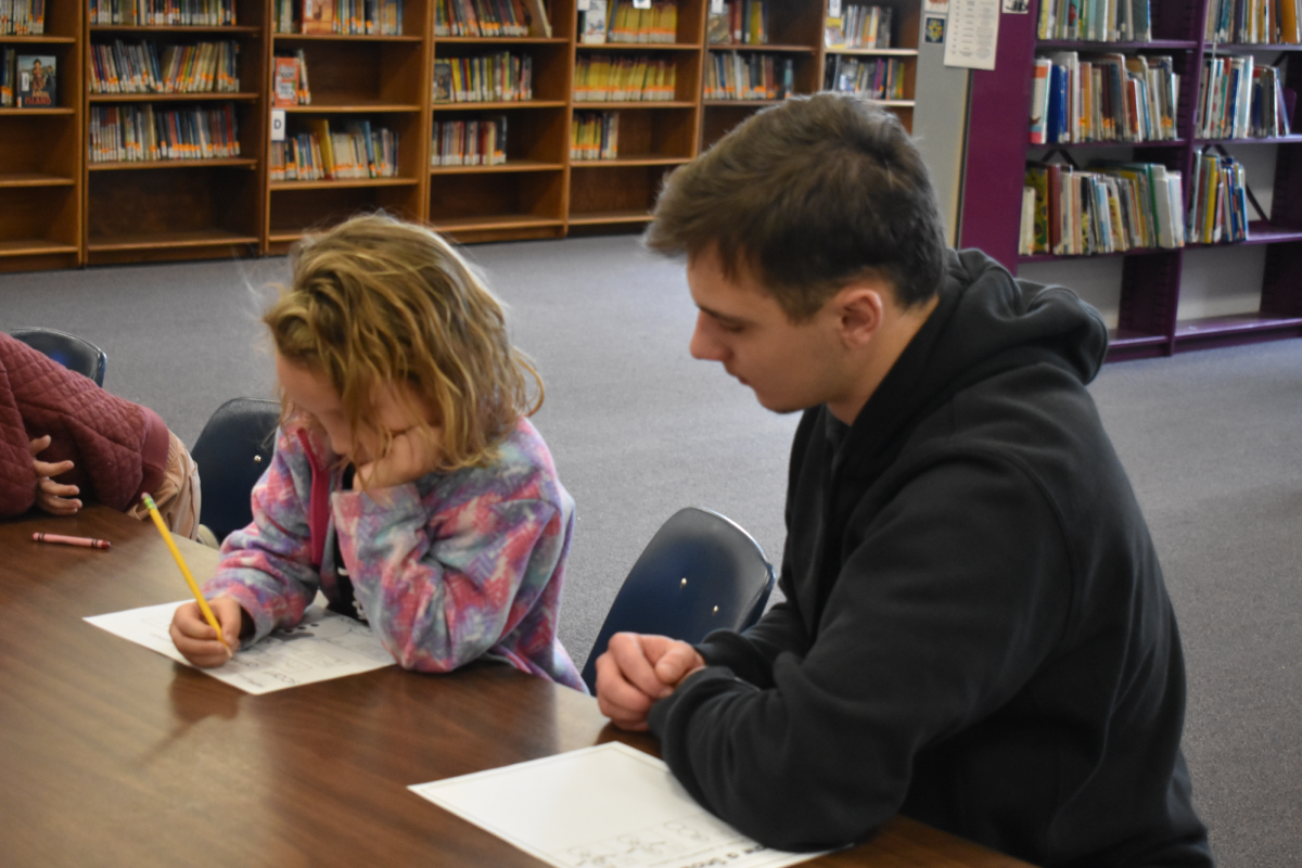 Liam Draper (12) working as an A+ aide with Haleigh Keyes (K) in the Elementary School Library