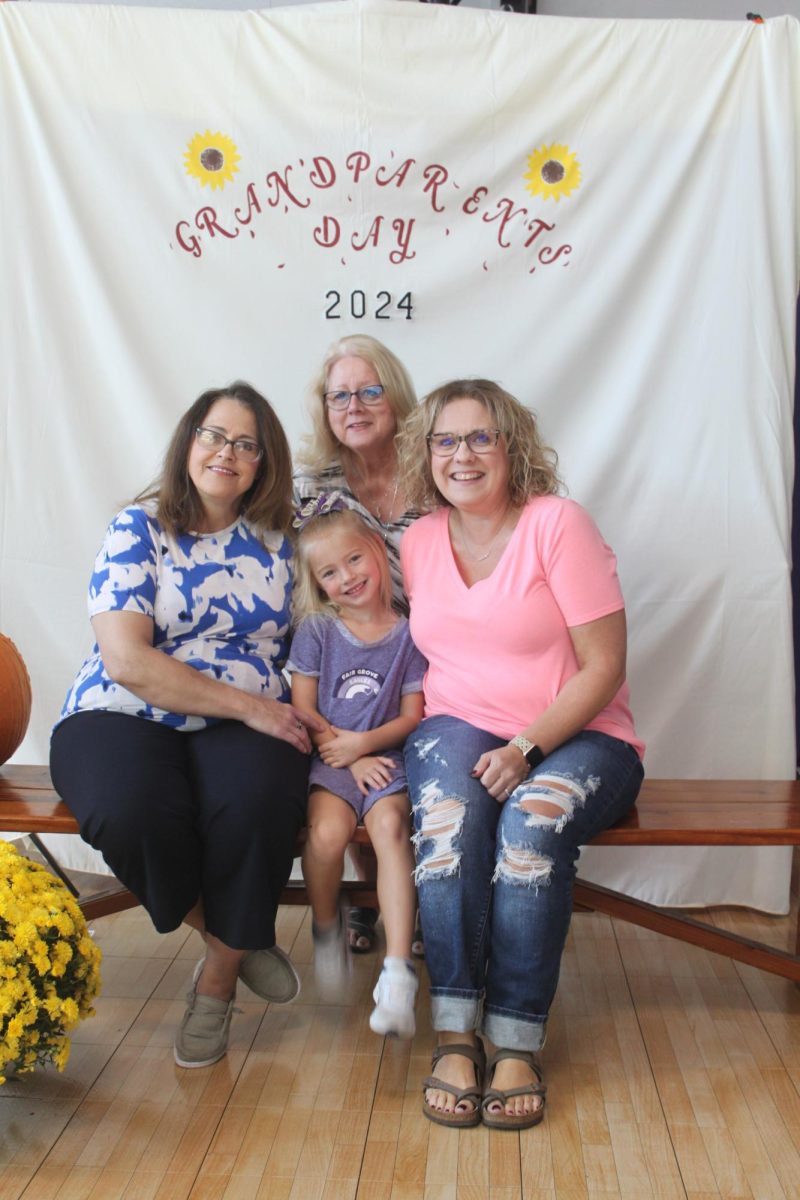 Vicky Knight and Stacia Nunley taking a group photo with their granddaughter Aurora Bradley on Grandparents Day in the lower Elementary gym. (From left to right: Vickie Knight, Aurora Bradley (K), Connie Peterson, Stacia Nunley)