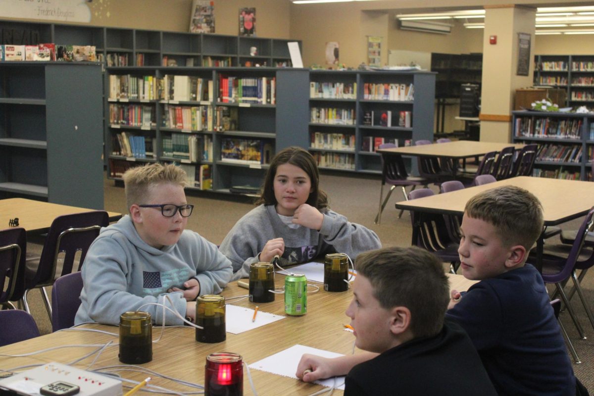 Baylen Booth (5), Bowen Benedict (5), Pier Johnson (5), and Maddox Steel (5), practicing with the buzzers in the high school library after school. 