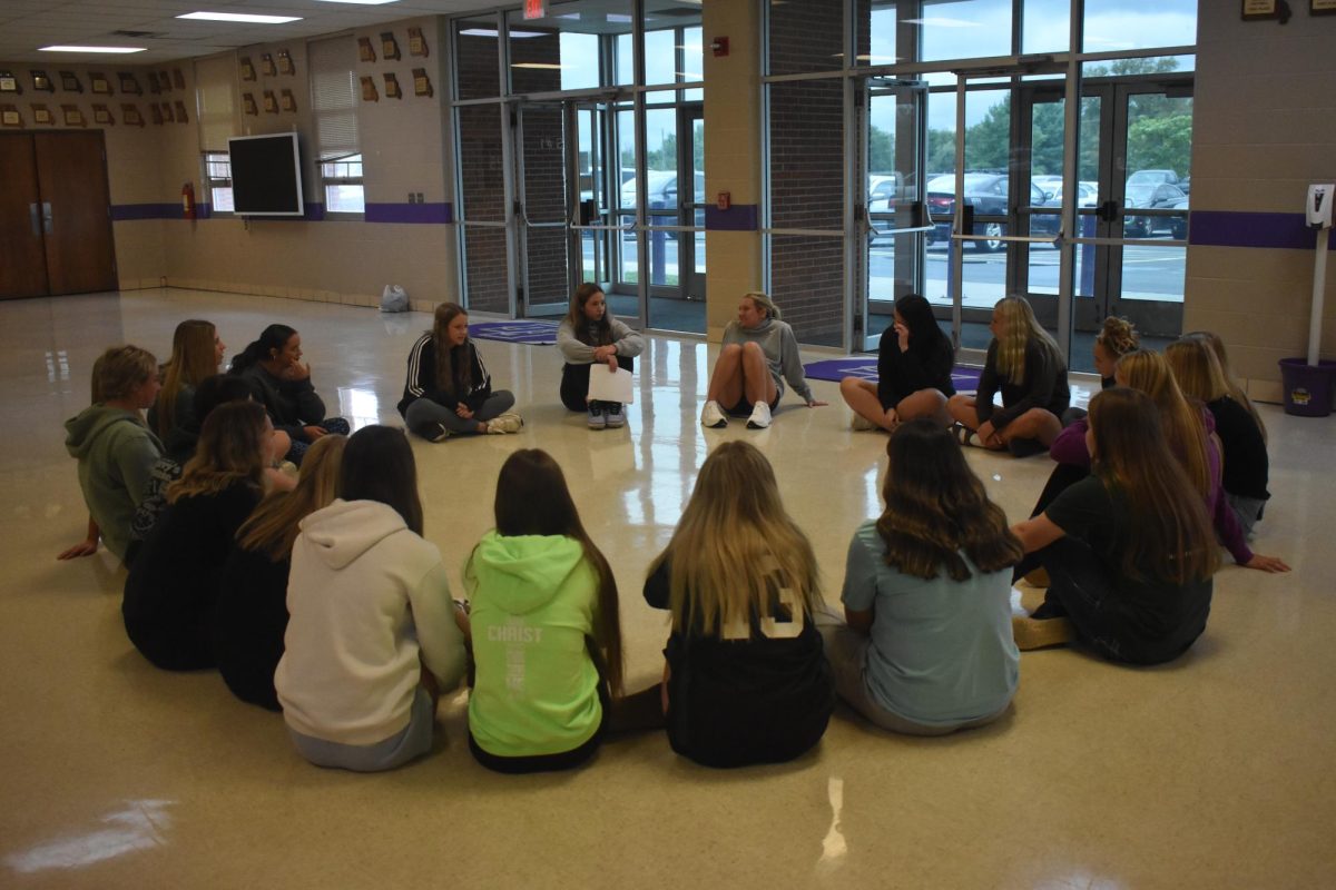 The SADD officers at the 9/13 SADD meeting speaking to other members in small groups around the high school gym.