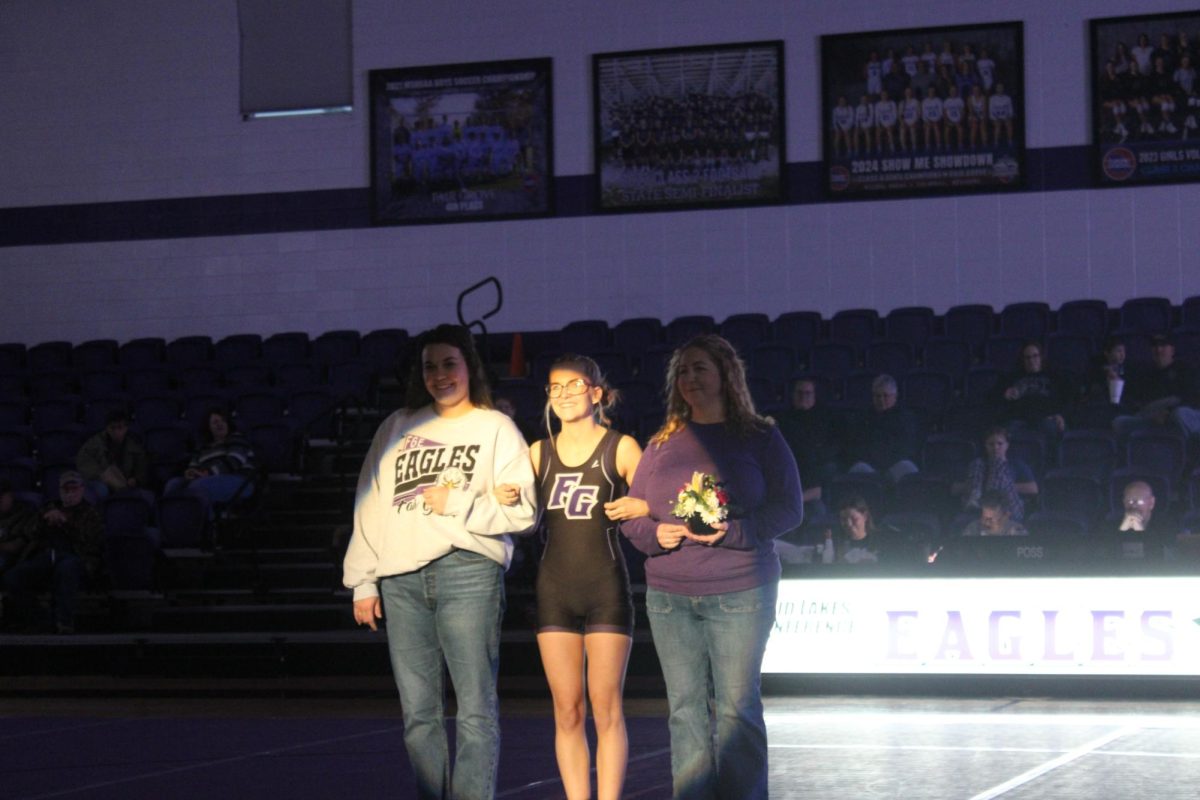 Riley Frazier (12) being escorted by Lauren Bledsoe and Sarah Frazier on wrestling senior night. 