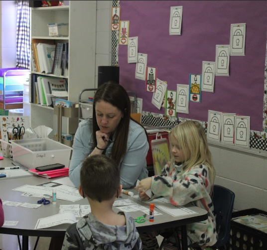 Mrs. Graves is engaged in teaching with Aubrey Rippe (2) next to her, and Luke Root (2) across the table from her. 