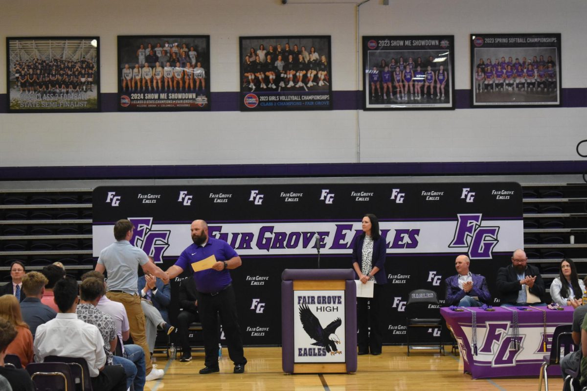 High School Football Coach Bill Voorhis awarded Carson Krider (12) with an award at the academic ceremony. 