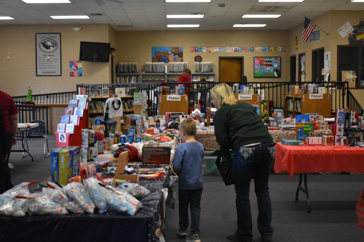An Elementary student shopping at the Holiday Shop with the help of a member of PTO. The PTO is in charge of many other events throughout the year. 