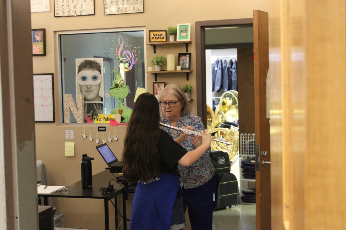 Cindy Sparks assisting a flute player in a beginning band, in Palomo's office. She is making sure she is playing correctly.