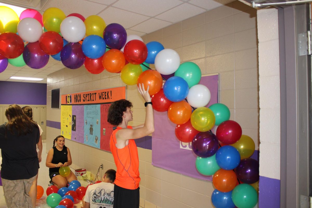 STUCO Members setting up a balloon archway for Homecoming. In the front is Cole Howard (9) holding up the balloons while Megan Bright (10) and Cinch Dowling (10), are helping blow up balloons behind him. This photo was taken by Miller Bettis.