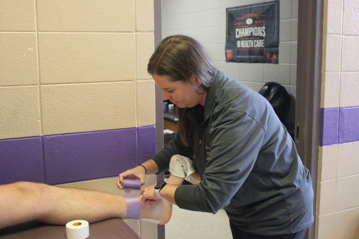 Kinsey Cook is wrapping an athlete's foot to prevent injuries. Cook has been a trainer for 10 years and has spent four years at Fair Grove. 