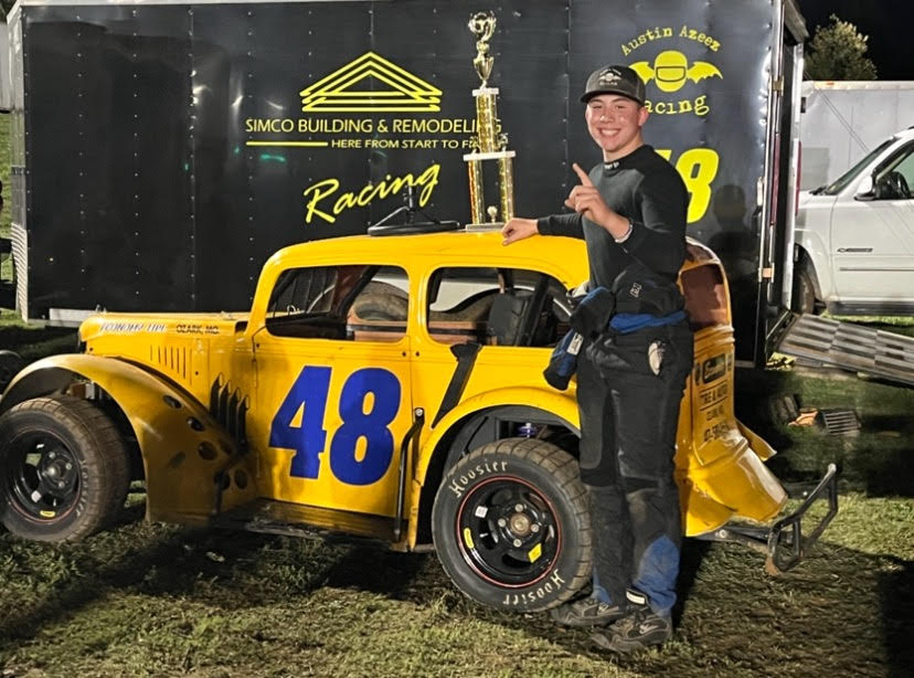 Austin Azeez (10) standing with his first place trophy and car after a racing event. 