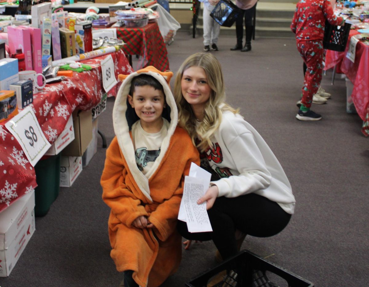 Maryah Wisley (10) and Ezra Smith (2) smiling for the camera at the 2025 Holiday Shop. The Holiday Shop is hosted by the PTO in the elementary school library.