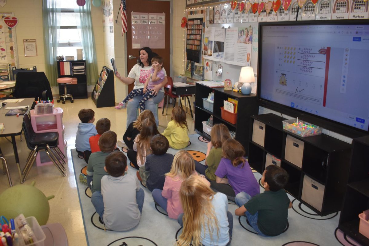 Mrs. Gore reading her Kindergarten class, "Cat in the Hat" by Dr. Seuss. Every day, these students sit on their "carpet spots" while Mrs. Gore reads a book to the class. 
Sitting on Mrs. Gore's lap is Kindergarten student Paisley Letterman. 