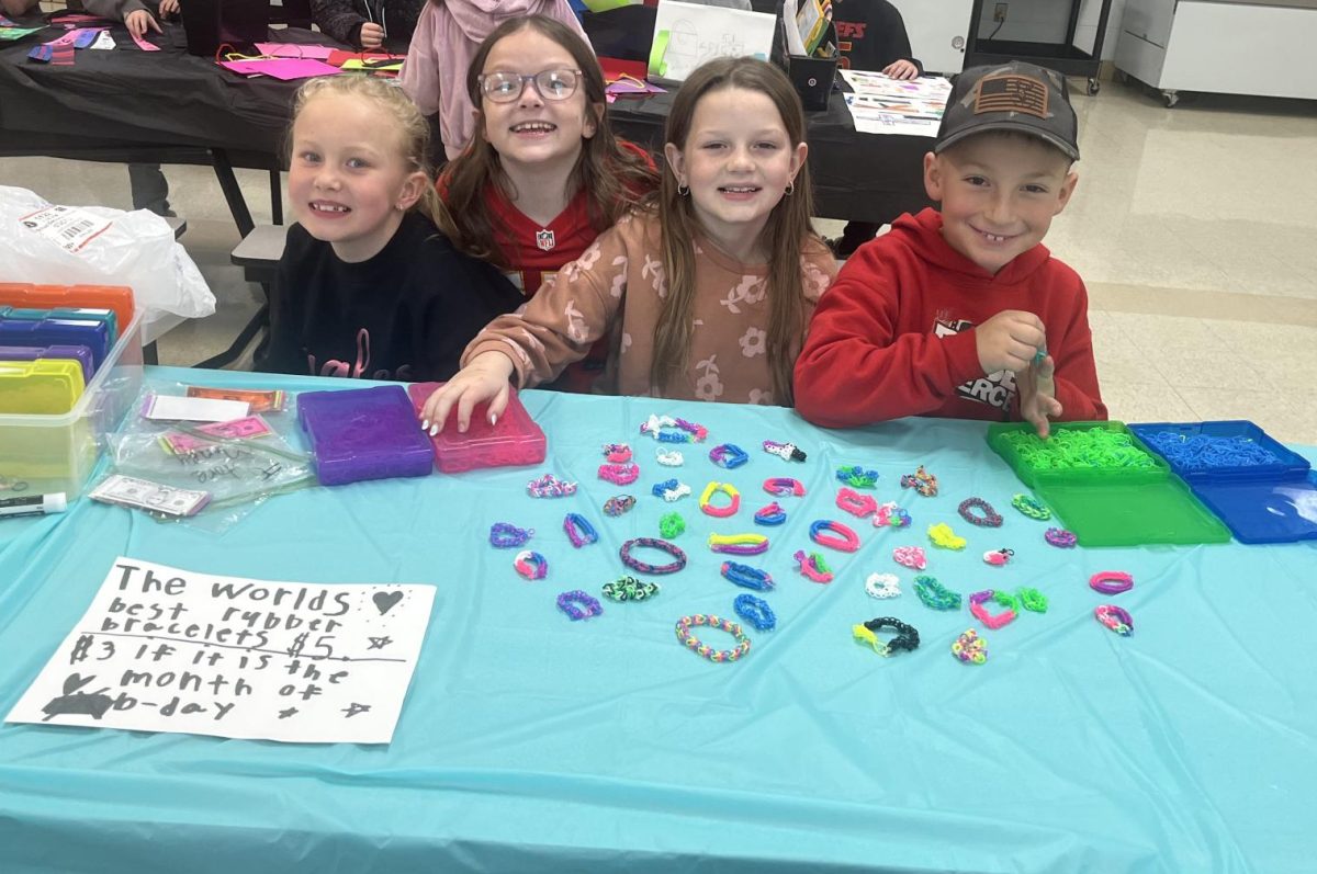Second graders Chaelynn Crim, Kayle Monday, Mylee Gettle, and Corbin Nivens smile proudly behind their bracelet stand during the second grade mall, showing off the handmade items created to sell to their classmates.
