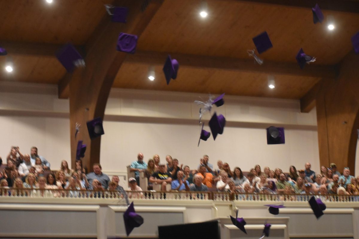 The class of 2025 at their graduation. They are throwing their caps at the end of their ceremony.
